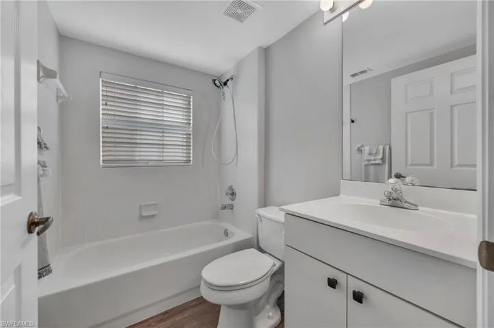 Bathroom with vanity, shower / washtub combination, and wood finished floors