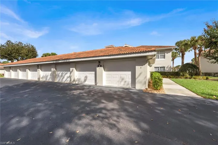 View of side of home with community garages, stucco siding, and a tile roof
