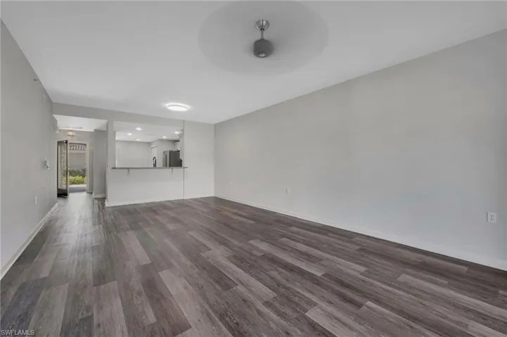 Unfurnished living room with dark wood-type flooring and ceiling fan