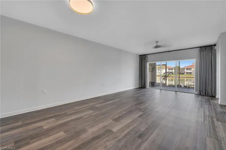 Empty room with dark wood-style flooring and a water view