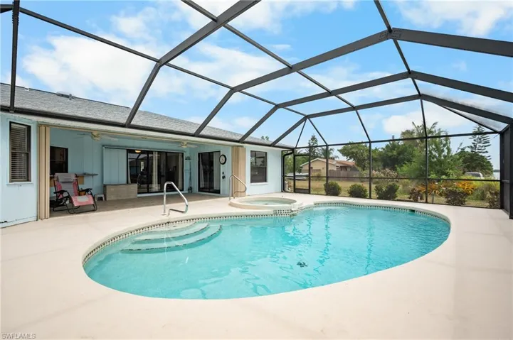 Screened enclosure featuring a freeform swimming pool with integrated spa and concrete decking