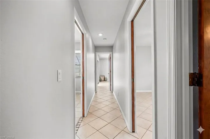 Central hallway featuring diagonal tile flooring, recessed lighting, and multiple doorways with wood trim