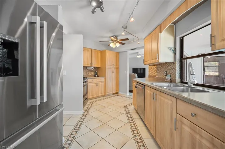 Kitchen featuring stainless steel appliances, light wood cabinetry, and a patterned tile floor