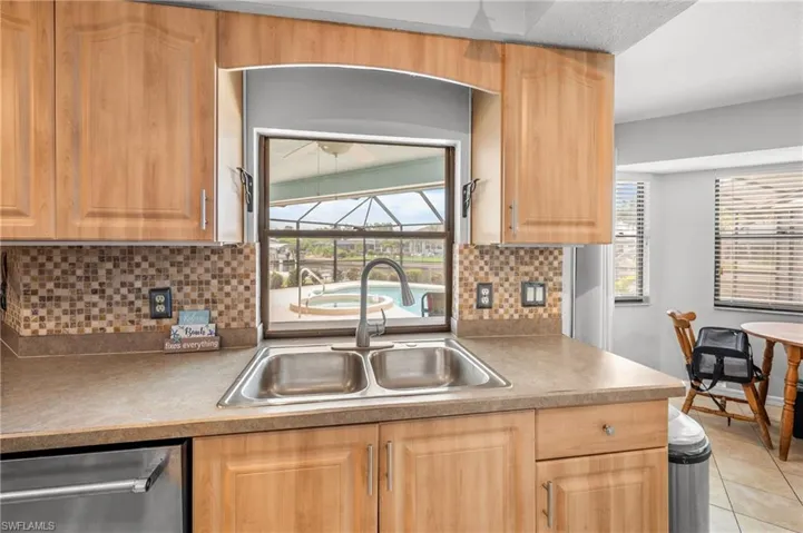 Kitchen featuring light wood cabinetry, a dual-basin stainless steel sink with a gooseneck faucet, and a mosaic tile backsplash