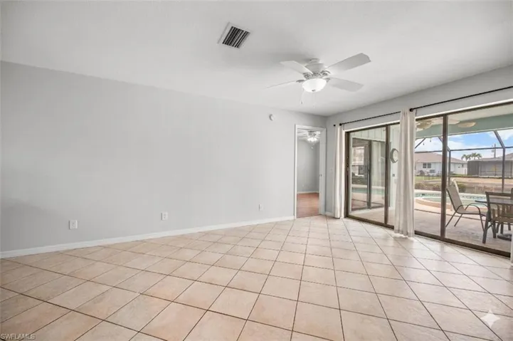 Tiled flooring throughout this open space, featuring multiple sliding glass doors opening to the screened patio with a pool