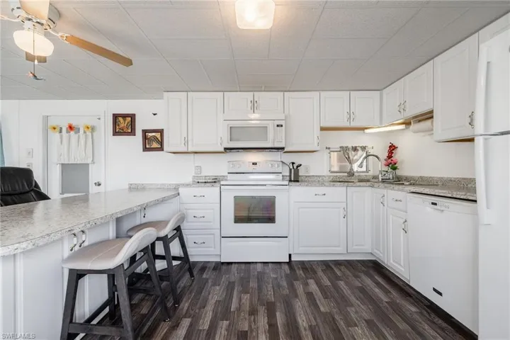 Kitchen with white appliances, a peninsula, and white cabinets