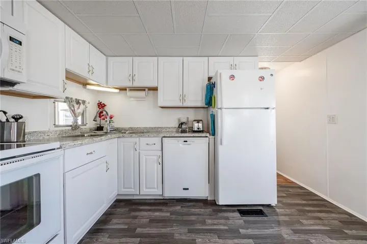 Kitchen featuring white cabinets, white appliances, and dark wood-style flooring