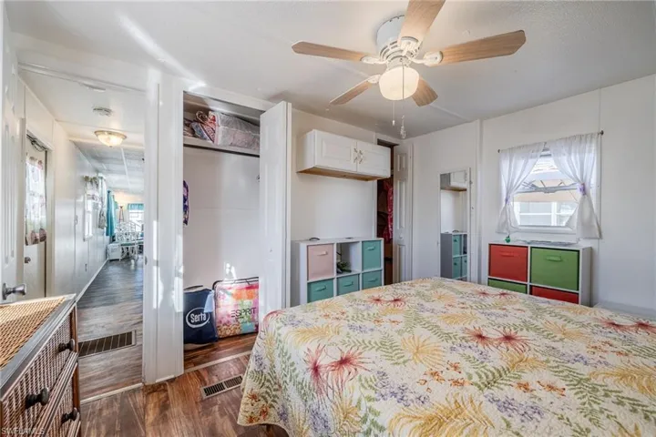Bedroom featuring a ceiling fan, wood finished floors, visible vents, and a closet