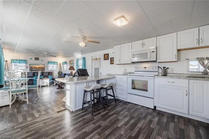 Kitchen with white appliances, white cabinets, a peninsula, and a wealth of natural light