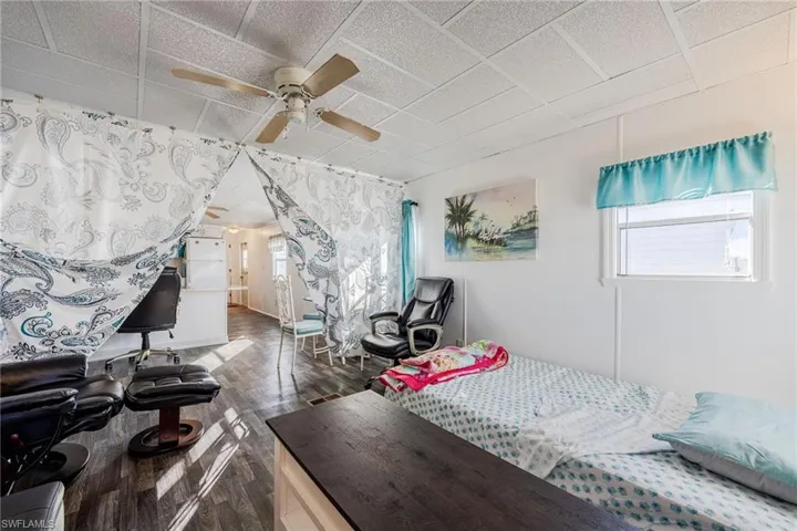 Bedroom featuring a paneled ceiling, dark wood-type flooring, and a ceiling fan