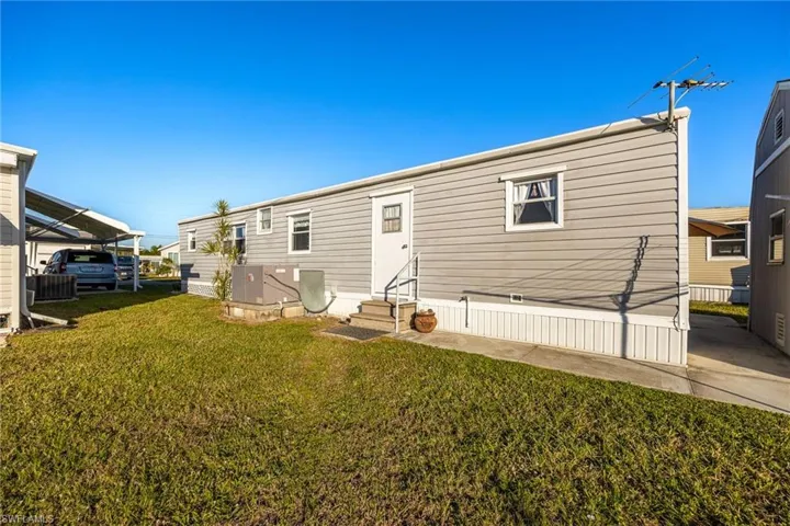 Rear view of property with entry steps, a yard, and central AC
