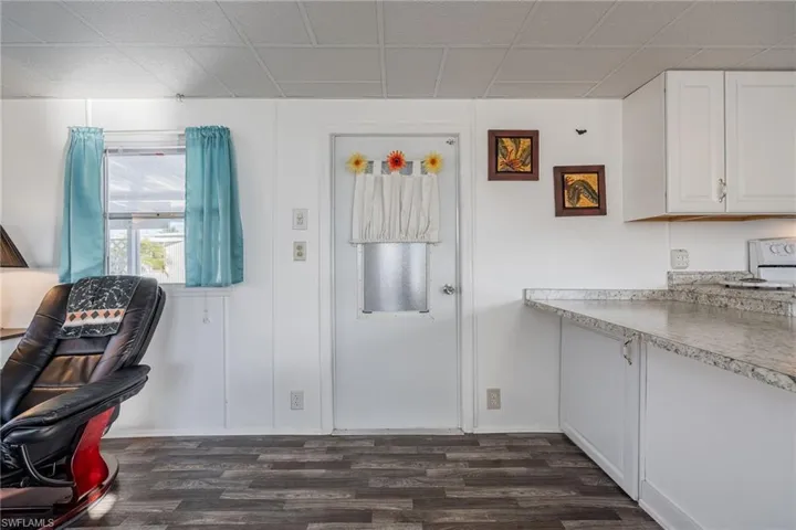 Kitchen featuring dark wood finished floors, light countertops, and white cabinetry
