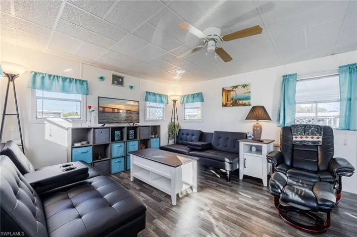 Living area featuring a ceiling fan, wood finished floors, and a wealth of natural light