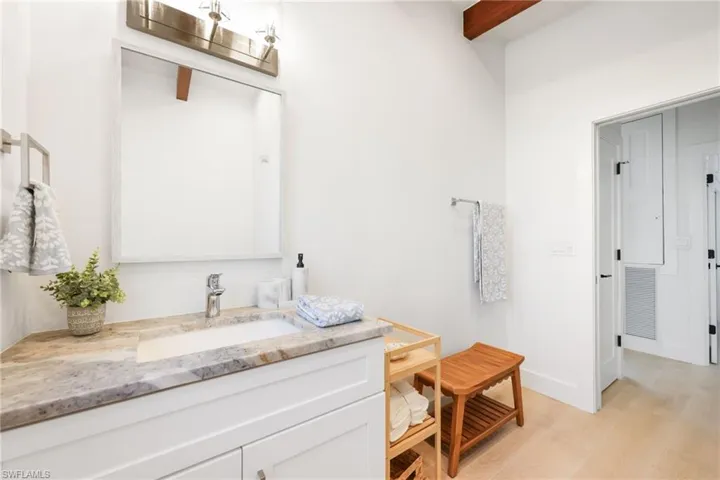 Bathroom with visible vents, vanity, wood finished floors, beamed ceiling, and baseboards