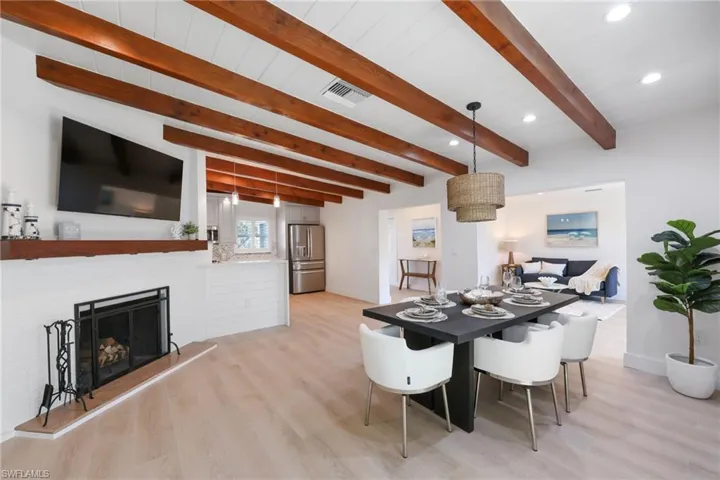 Dining area featuring light wood-style floors, visible vents, a fireplace with raised hearth, and baseboards