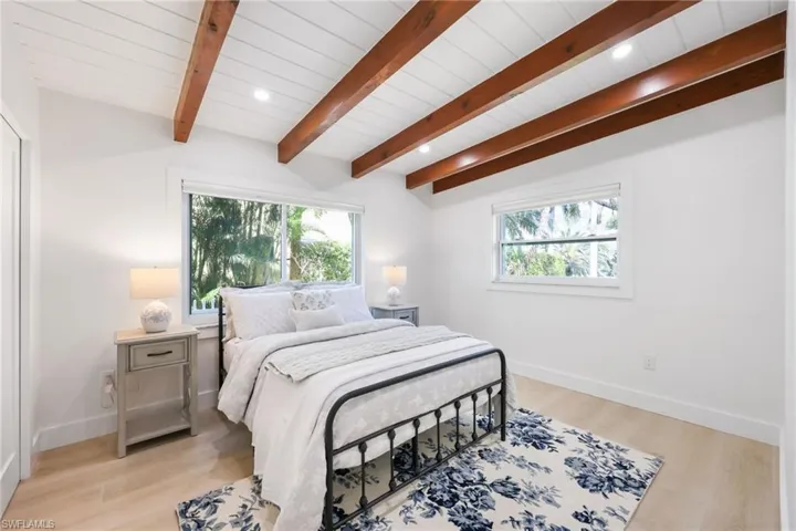 Bedroom featuring multiple windows, beam ceiling, and light wood-style floors