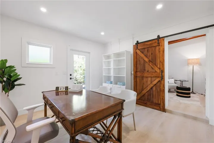 Office area with recessed lighting, light wood finished floors, and a barn door