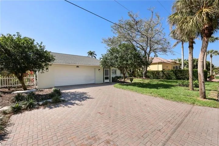 Ranch-style house with a garage, decorative driveway, a front yard, and stucco siding
