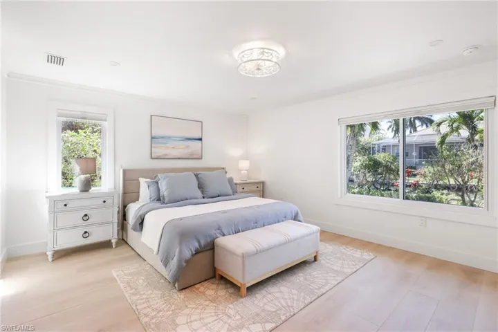 Bedroom featuring light wood-style flooring, multiple windows, and visible vents