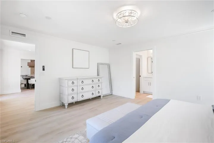 Bedroom featuring crown molding, light wood finished floors, visible vents, and baseboards