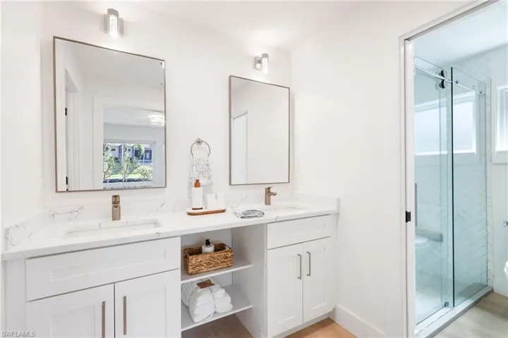 Bathroom with double vanity, a shower stall, toilet, and a sink