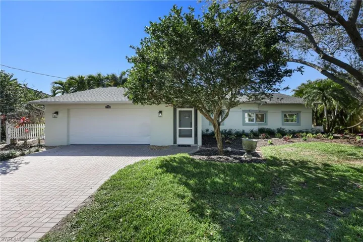 Ranch-style home with a garage, fence, decorative driveway, a front yard, and stucco siding