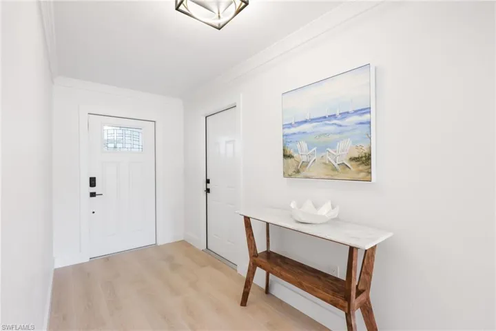 Foyer entrance with crown molding, light wood-style flooring, and baseboards