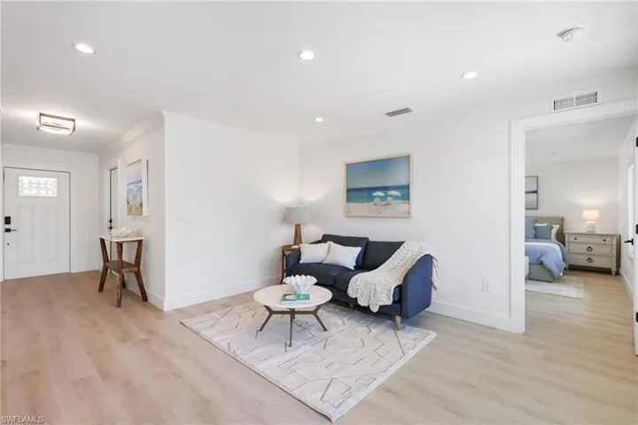 Living area featuring baseboards, visible vents, crown molding, and light wood finished floors