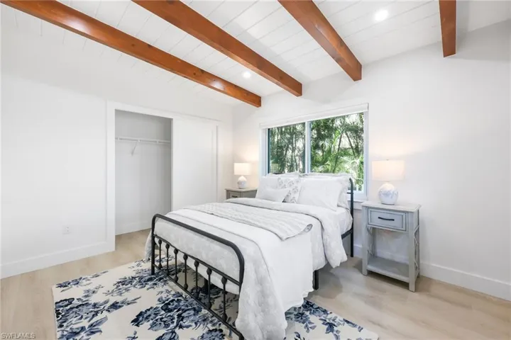 Bedroom featuring baseboards, lofted ceiling with beams, wooden ceiling, light wood-style floors, and a closet