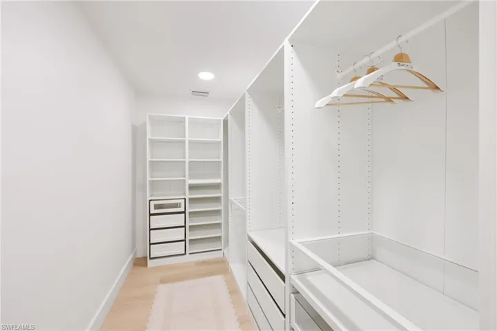 Spacious closet with light wood-style flooring and visible vents