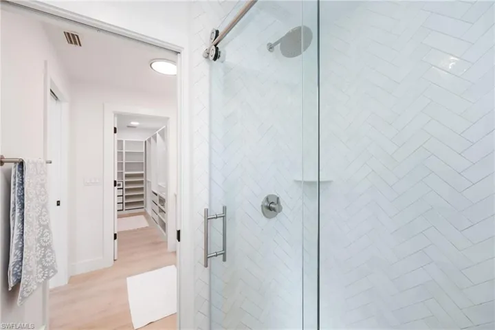 Full bath featuring a spacious closet, wood finished floors, a shower stall, and visible vents