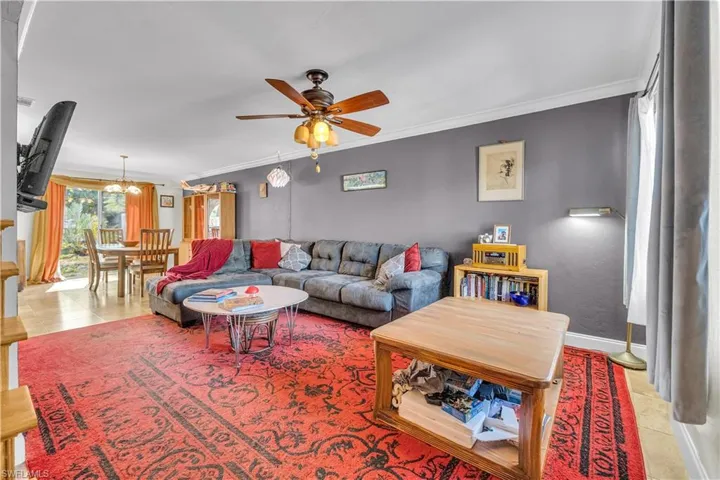 Tiled living room featuring crown molding, ceiling fan, and hanging lights