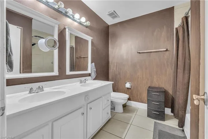 Full bathroom with double vanity, light tile patterned floors, and shower / bath combo