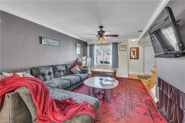 Living area featuring ornamental molding, ceiling fan, and a textured wall