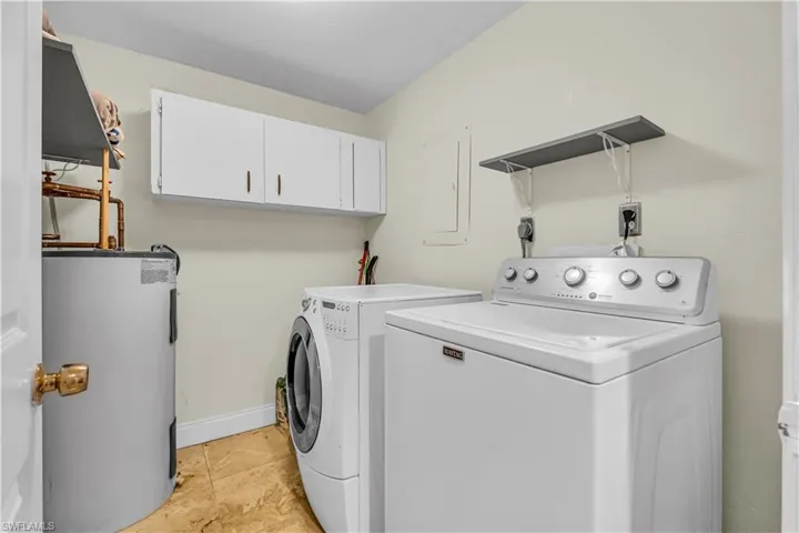 Laundry room with electric water heater, separate washer and dryer, cabinet space, and electric panel