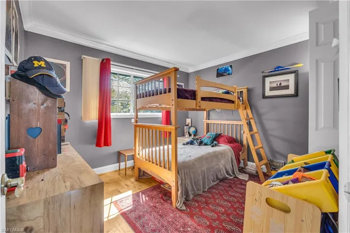 Bedroom with light wood finished floors and crown molding