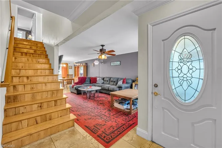 Foyer entrance featuring crown molding, light tile patterned floors, and ceiling fan