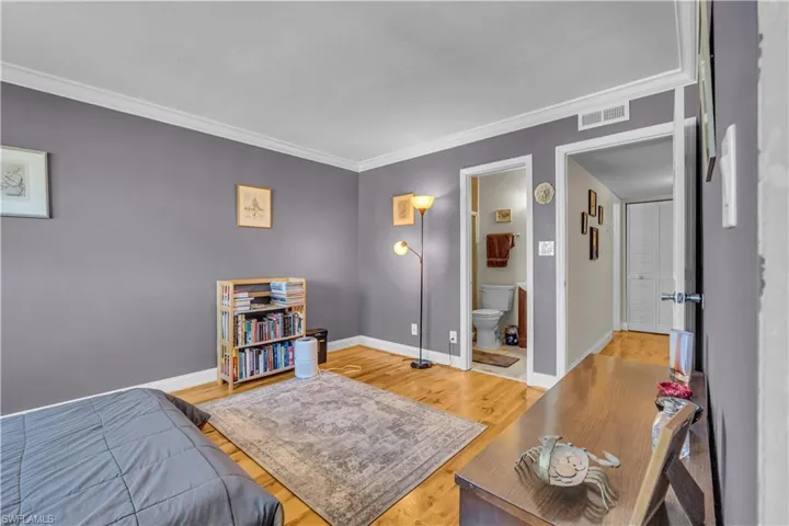 Bedroom featuring light wood-style flooring, ornamental molding, and ensuite bathroom