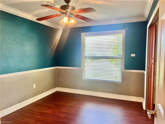 Empty room featuring ceiling fan, ornamental molding, and dark wood-type flooring