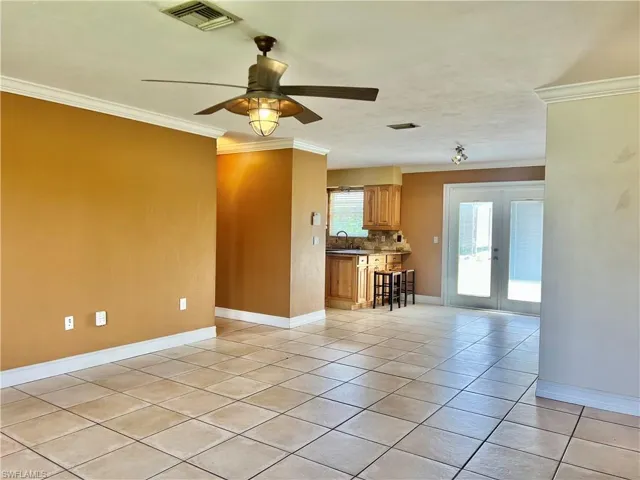Unfurnished living room with french doors, ceiling fan, crown molding, sink, and light tile patterned flooring
