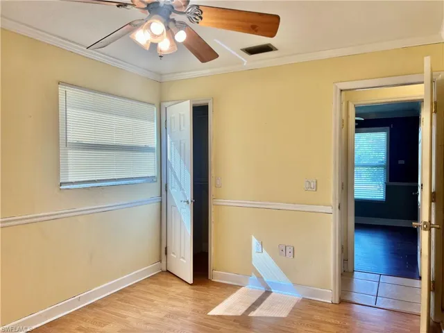 Empty room featuring light hardwood / wood-style flooring, ceiling fan, and crown molding