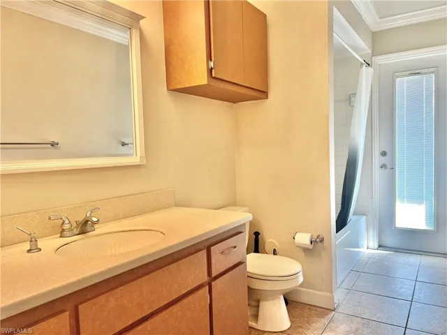 Full bathroom featuring shower / bathtub combination with curtain, tile patterned floors, toilet, vanity, and ornamental molding