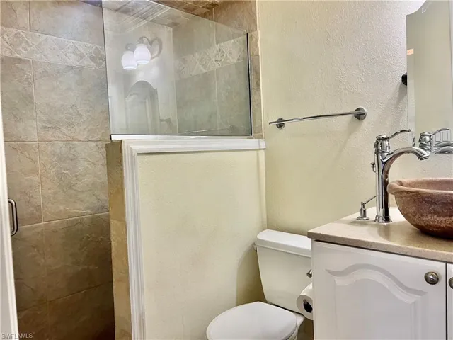 Bathroom featuring vanity, toilet, and an enclosed shower