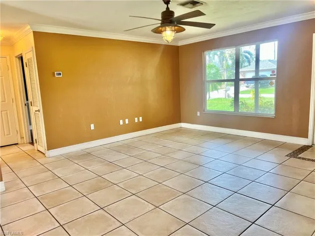 Spare room featuring light tile patterned floors, ceiling fan, and ornamental molding