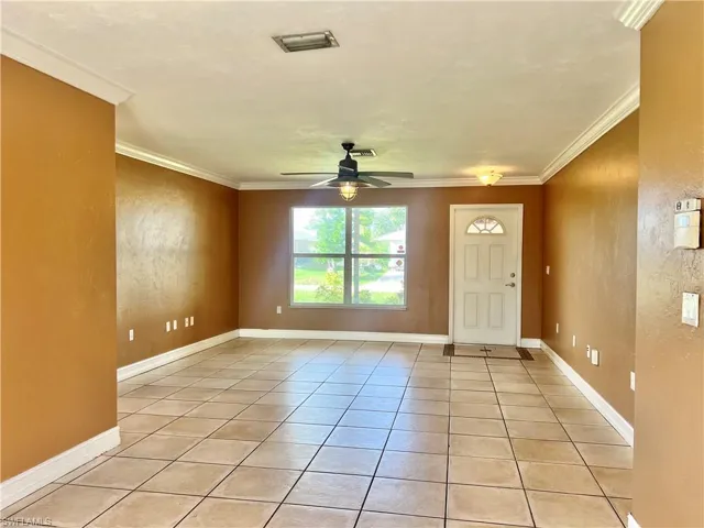 Tiled entryway with crown molding and ceiling fan