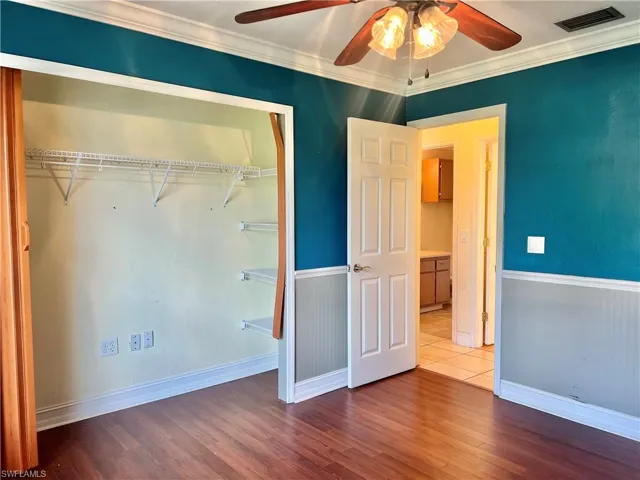 Unfurnished bedroom featuring hardwood / wood-style floors, ceiling fan, ornamental molding, and a closet