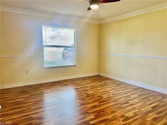 Empty room with ceiling fan, wood-type flooring, and crown molding