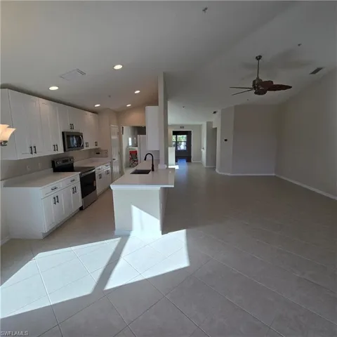 Kitchen featuring appliances with stainless steel finishes, white cabinetry, vaulted ceiling, recessed lighting, and open floor plan