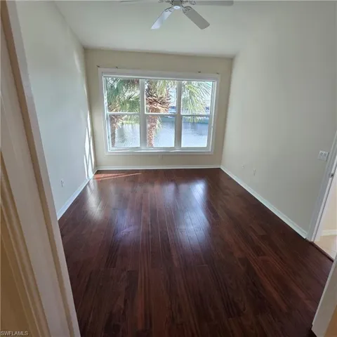 Spare room with dark wood-type flooring and a ceiling fan