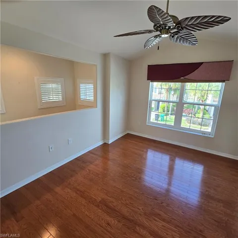 Unfurnished room with vaulted ceiling, a ceiling fan, dark wood finished floors, and healthy amount of natural light